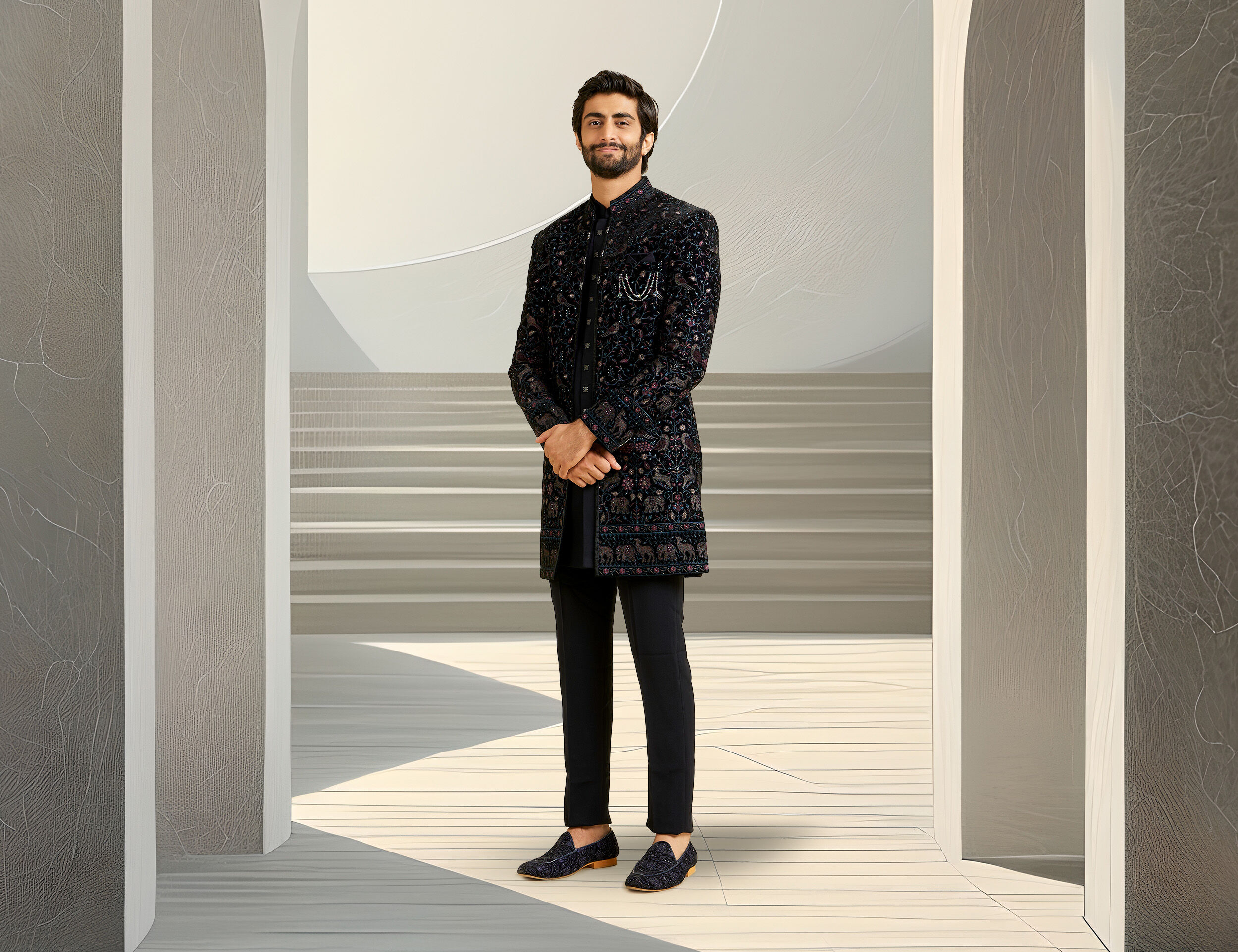 A groom dressed in a dark blue Indo-Western sherwani featuring intricate designs, perfect for a modern wedding look